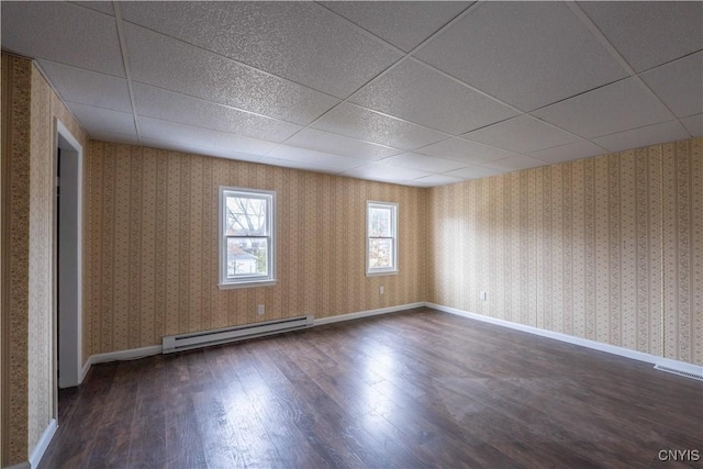 unfurnished room with a drop ceiling, dark hardwood / wood-style flooring, and baseboard heating