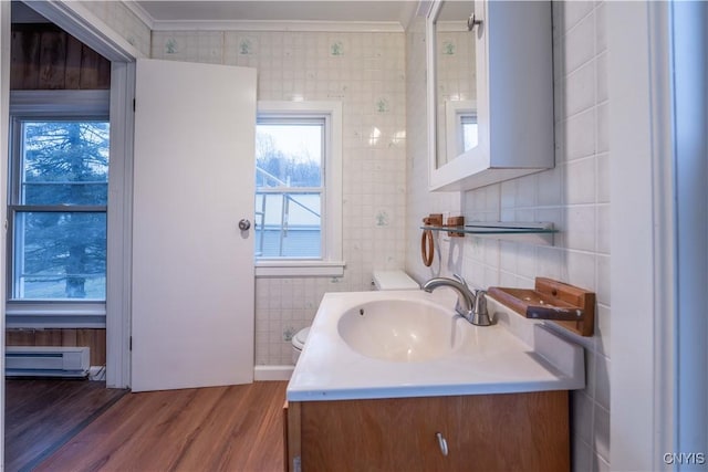 bathroom with baseboard heating, crown molding, hardwood / wood-style floors, vanity, and tile walls