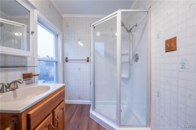 bathroom featuring hardwood / wood-style floors, vanity, ornamental molding, walk in shower, and tile walls