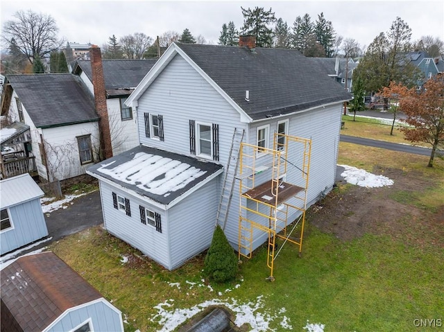 rear view of property with a storage shed and a yard