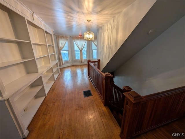 hallway with a chandelier and wood-type flooring