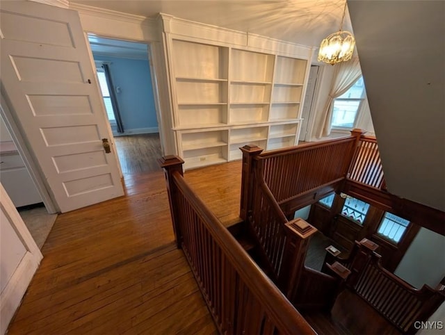 stairs with a chandelier, hardwood / wood-style flooring, and crown molding