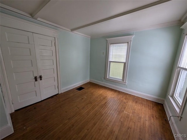 empty room featuring beam ceiling, dark hardwood / wood-style floors, and crown molding