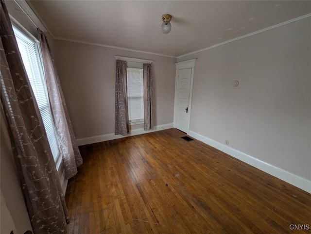 empty room featuring wood-type flooring and ornamental molding