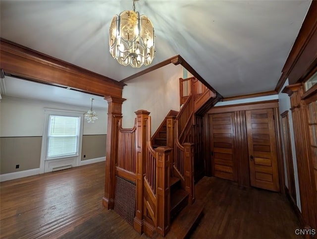 stairway with hardwood / wood-style flooring, crown molding, and a chandelier