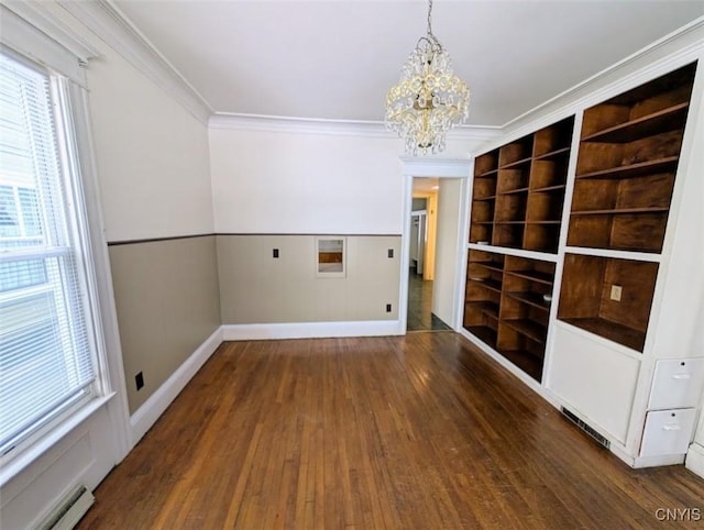 empty room featuring dark hardwood / wood-style floors, ornamental molding, baseboard heating, and a chandelier