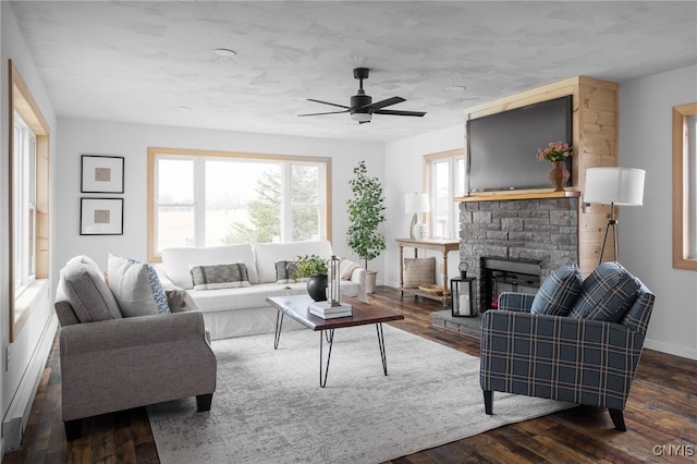 living room with dark hardwood / wood-style flooring, a stone fireplace, and ceiling fan