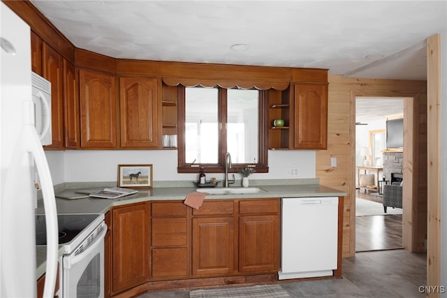 kitchen with a stone fireplace, sink, white appliances, and light hardwood / wood-style flooring