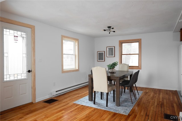 dining space with light hardwood / wood-style flooring, a wealth of natural light, and a baseboard radiator