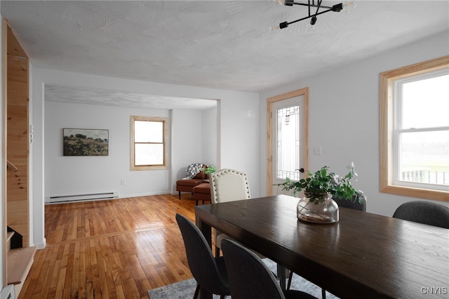 dining room with wood-type flooring, a textured ceiling, and a baseboard heating unit