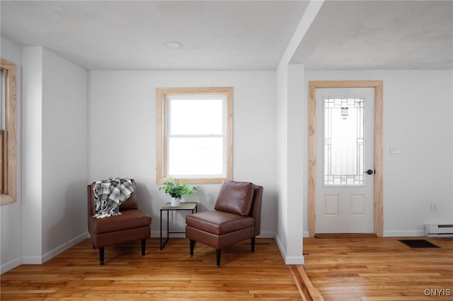 living area featuring light hardwood / wood-style flooring and a baseboard heating unit