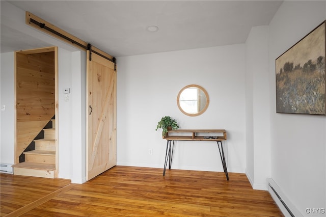 hallway featuring hardwood / wood-style flooring, a barn door, and a baseboard heating unit