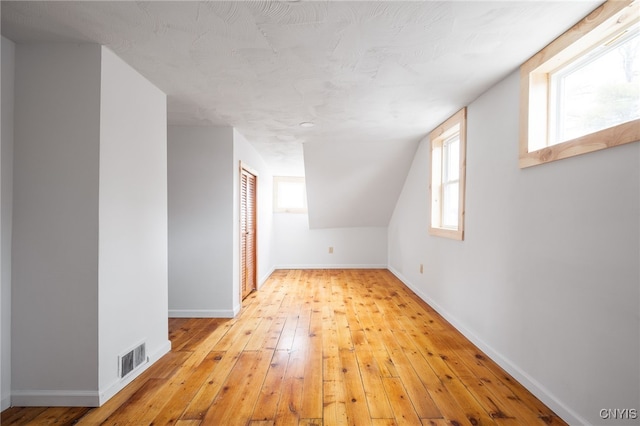 bonus room with vaulted ceiling and light hardwood / wood-style flooring