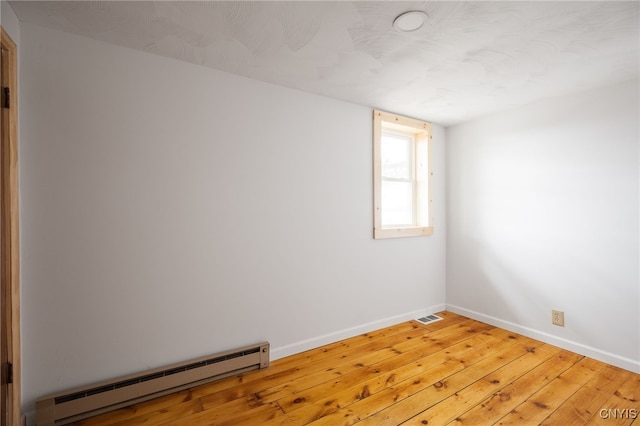 empty room with a baseboard radiator and hardwood / wood-style flooring