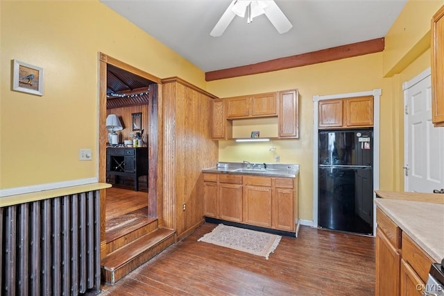 kitchen with ceiling fan, black refrigerator, dark hardwood / wood-style flooring, and sink