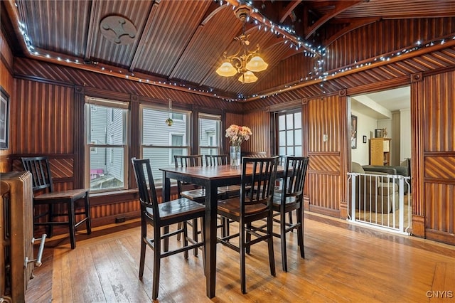 dining space featuring wood ceiling, vaulted ceiling, wooden walls, a chandelier, and hardwood / wood-style floors