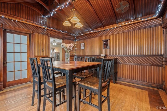 dining room featuring wooden walls, ceiling fan, light hardwood / wood-style floors, and wooden ceiling