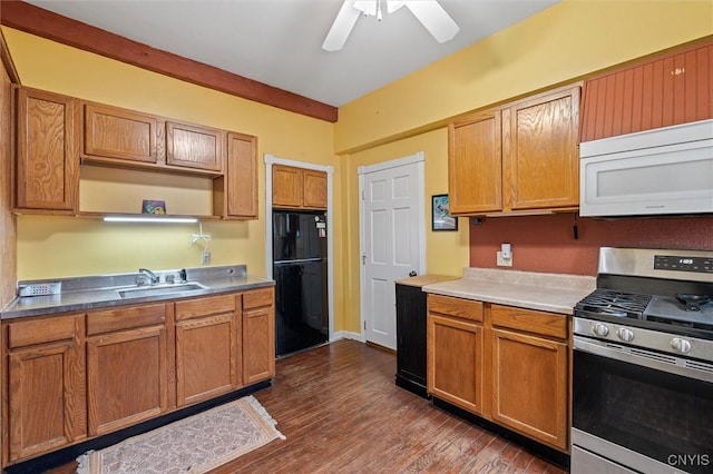 kitchen featuring black fridge, sink, gas range, ceiling fan, and dark hardwood / wood-style flooring