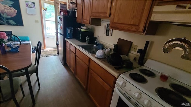 kitchen with stainless steel fridge, electric stove, sink, and light hardwood / wood-style flooring