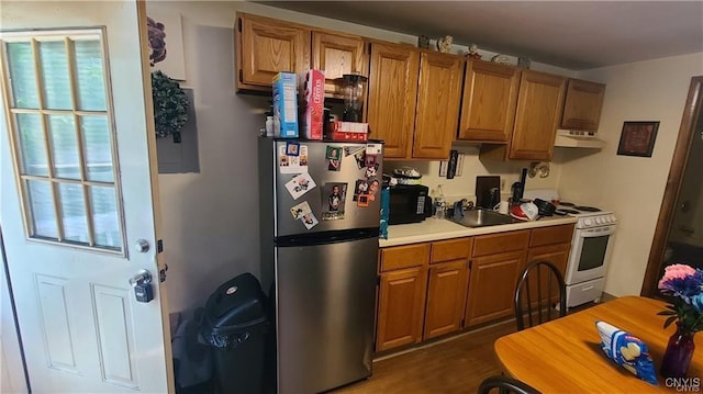 kitchen with white stove, dark hardwood / wood-style floors, stainless steel refrigerator, and sink