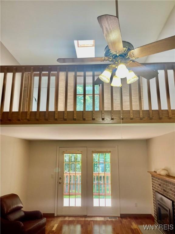 interior space with a high ceiling, a skylight, ceiling fan, and hardwood / wood-style flooring