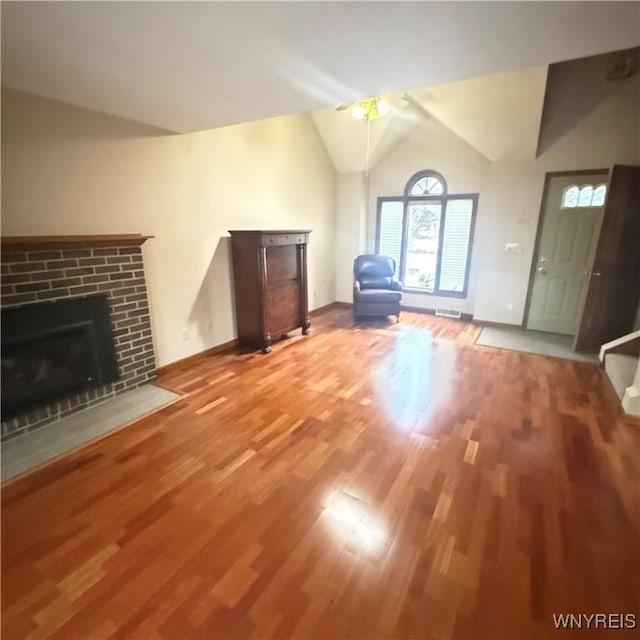 unfurnished living room featuring ceiling fan, a fireplace, lofted ceiling, and hardwood / wood-style flooring