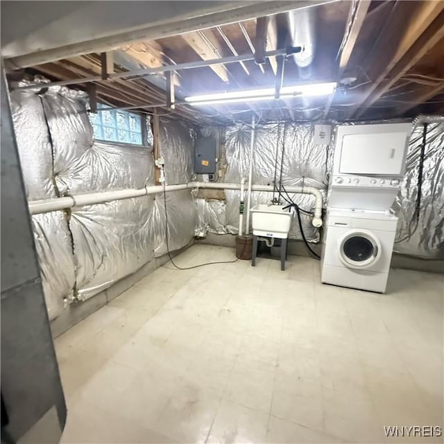 basement with electric panel, stacked washer / drying machine, and sink