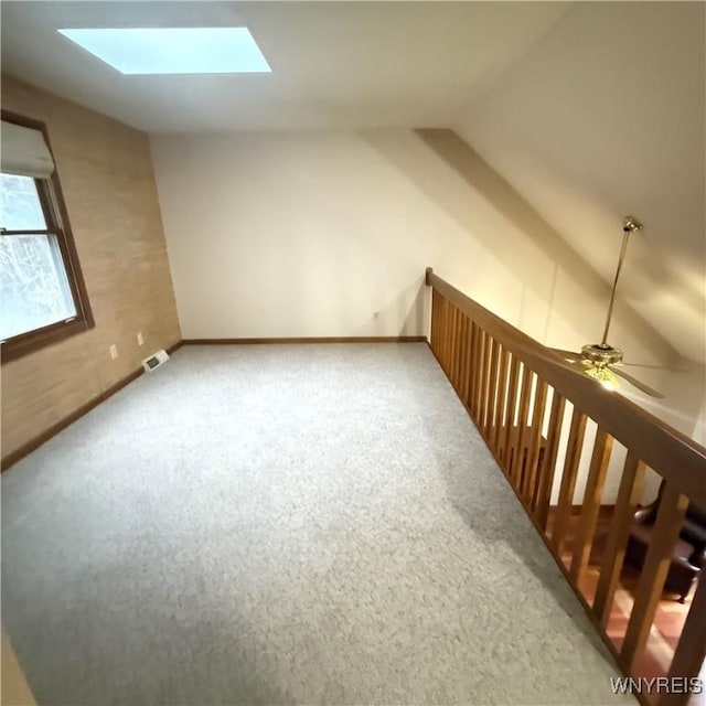 additional living space with carpet flooring, ceiling fan, and lofted ceiling with skylight