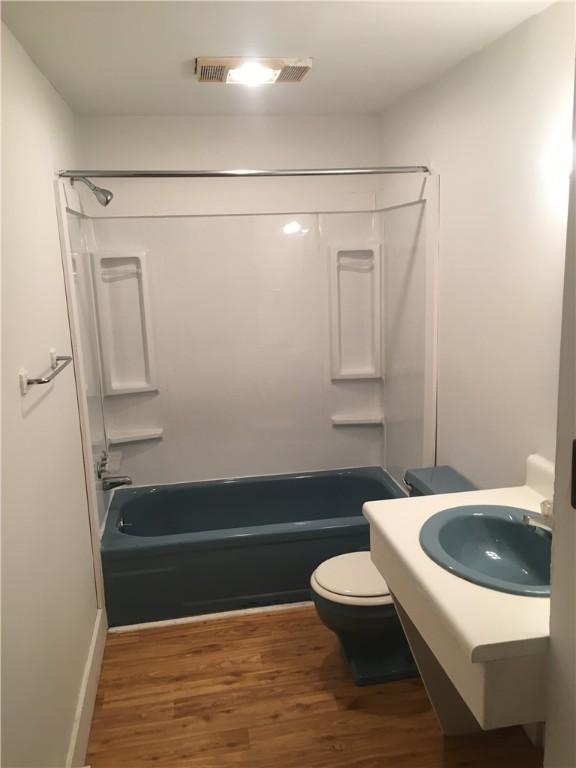 full bathroom featuring hardwood / wood-style floors, toilet, sink, and bathtub / shower combination