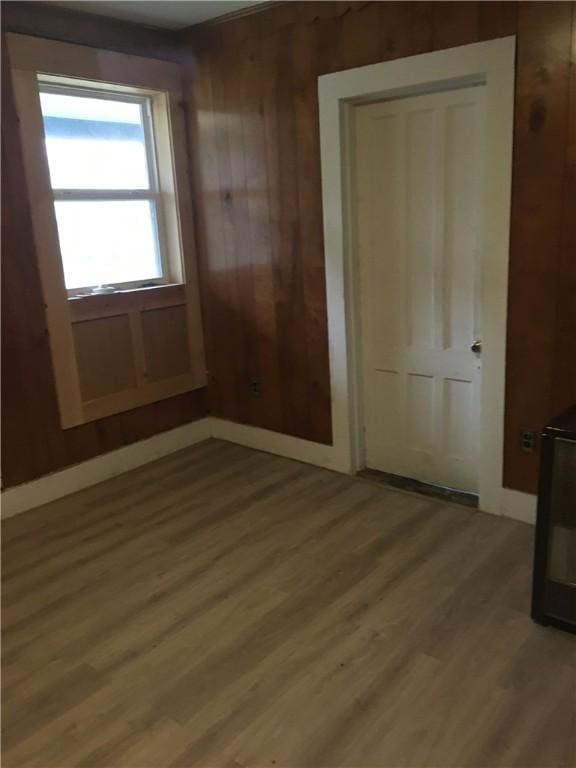 unfurnished bedroom with wood-type flooring, a closet, and wooden walls