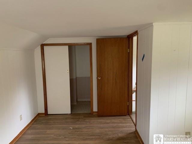 hallway with dark hardwood / wood-style flooring and vaulted ceiling