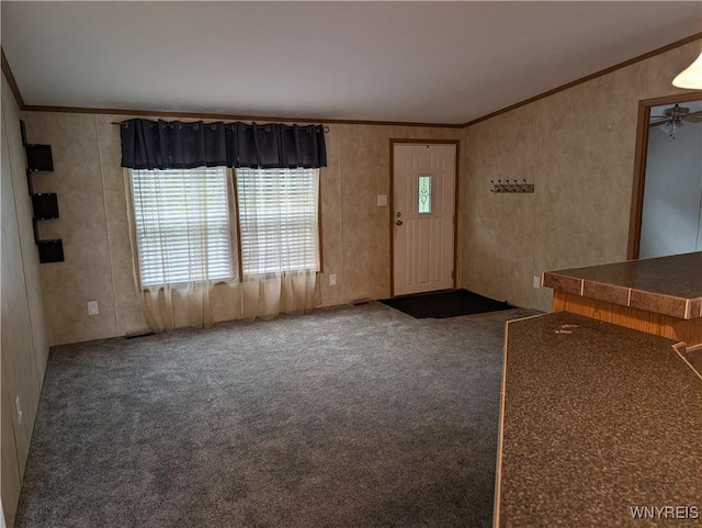 foyer entrance featuring dark colored carpet, ceiling fan, and ornamental molding