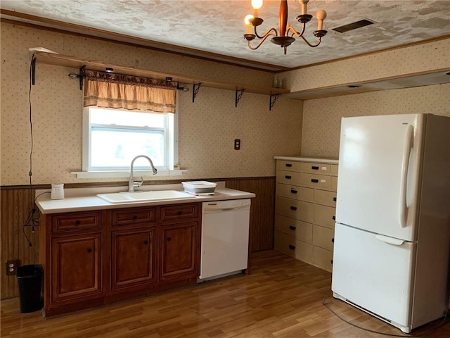 kitchen with a textured ceiling, light hardwood / wood-style flooring, hanging light fixtures, and white appliances