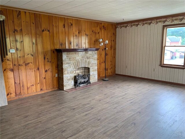 unfurnished living room featuring wood walls, wood-type flooring, and a fireplace