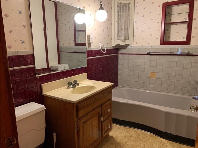 bathroom with vanity, a tub to relax in, toilet, and tile walls