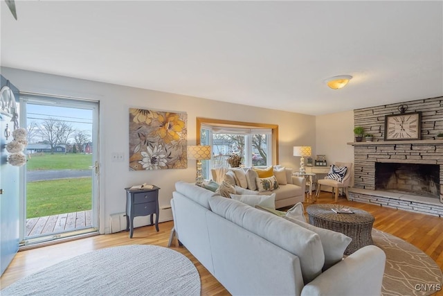 living room with a fireplace, light hardwood / wood-style flooring, and a baseboard heating unit