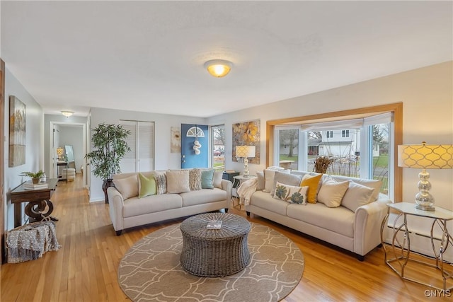 living room featuring baseboard heating, a healthy amount of sunlight, and light hardwood / wood-style floors