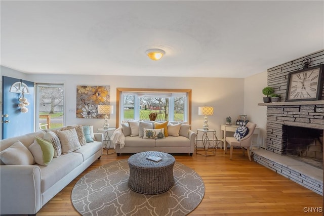 living room featuring light wood-type flooring and a stone fireplace