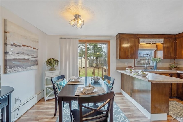 dining space featuring baseboard heating, light hardwood / wood-style flooring, and sink