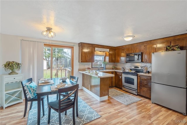 kitchen with kitchen peninsula, light hardwood / wood-style flooring, stainless steel appliances, and sink