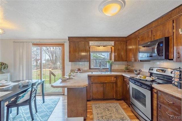 kitchen with stainless steel appliances, plenty of natural light, light hardwood / wood-style floors, and sink