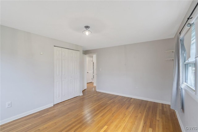 unfurnished bedroom featuring light hardwood / wood-style floors, a closet, and multiple windows