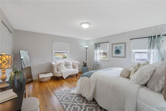 bedroom with light hardwood / wood-style floors, baseboard heating, and multiple windows