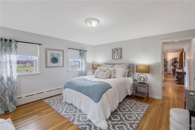 bedroom with light hardwood / wood-style flooring and baseboard heating