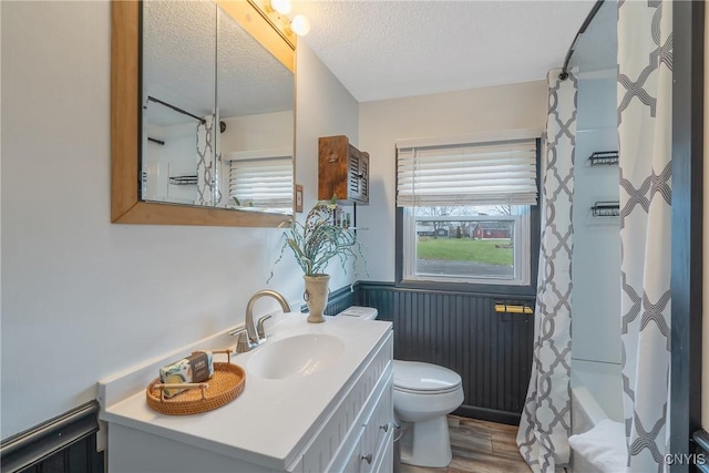 full bathroom featuring vanity, shower / bath combo, toilet, a textured ceiling, and wood-type flooring