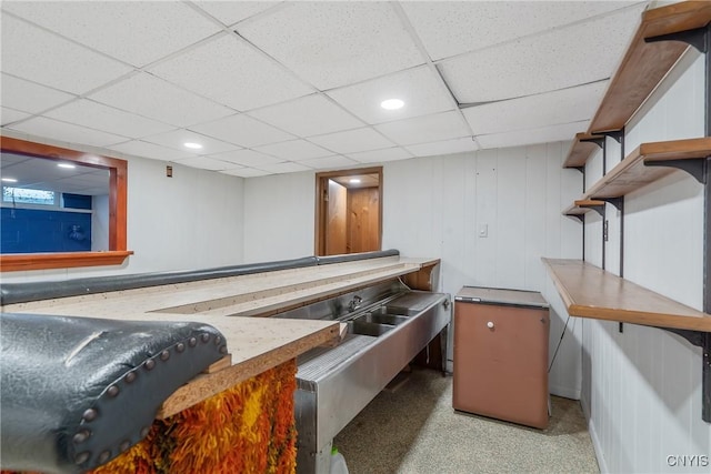 bar featuring a paneled ceiling, light carpet, and wood walls