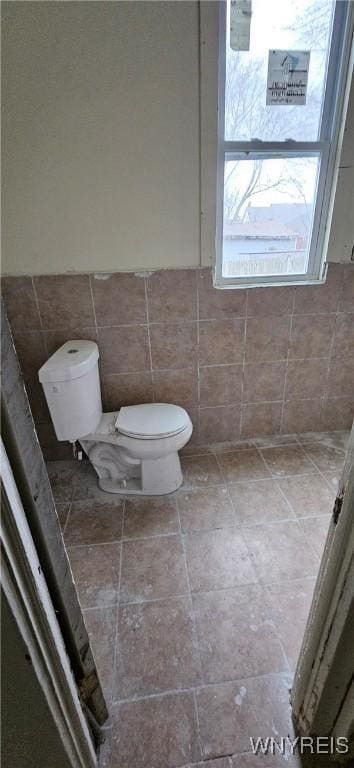 bathroom with toilet and tile walls