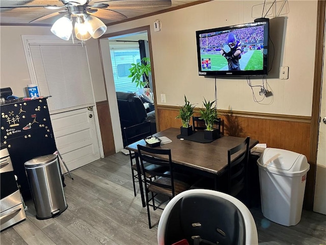 dining space featuring hardwood / wood-style flooring, ceiling fan, and wooden walls