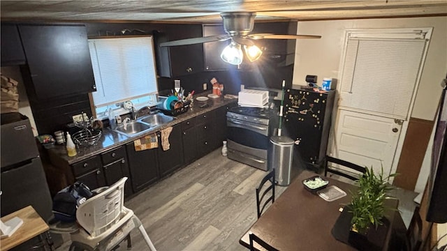 kitchen featuring ceiling fan, stainless steel electric stove, wooden walls, sink, and light hardwood / wood-style floors