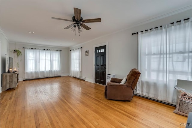 living area featuring ceiling fan, a baseboard heating unit, crown molding, and light hardwood / wood-style flooring